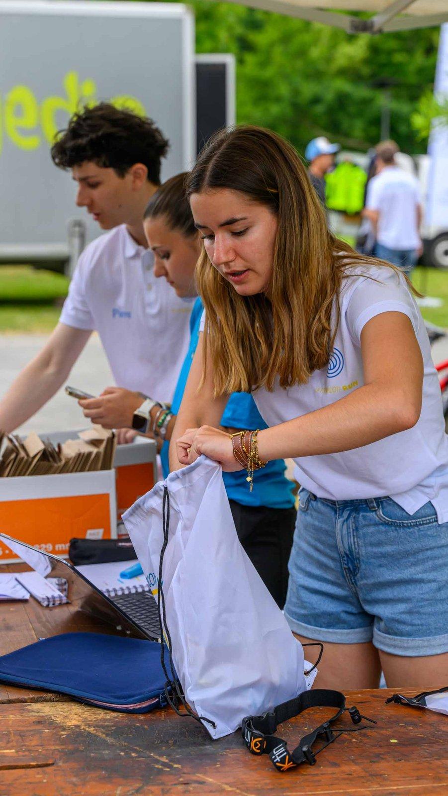 Trois bénévoles de l'équipe organisatrice préparent les sacs des coureurs