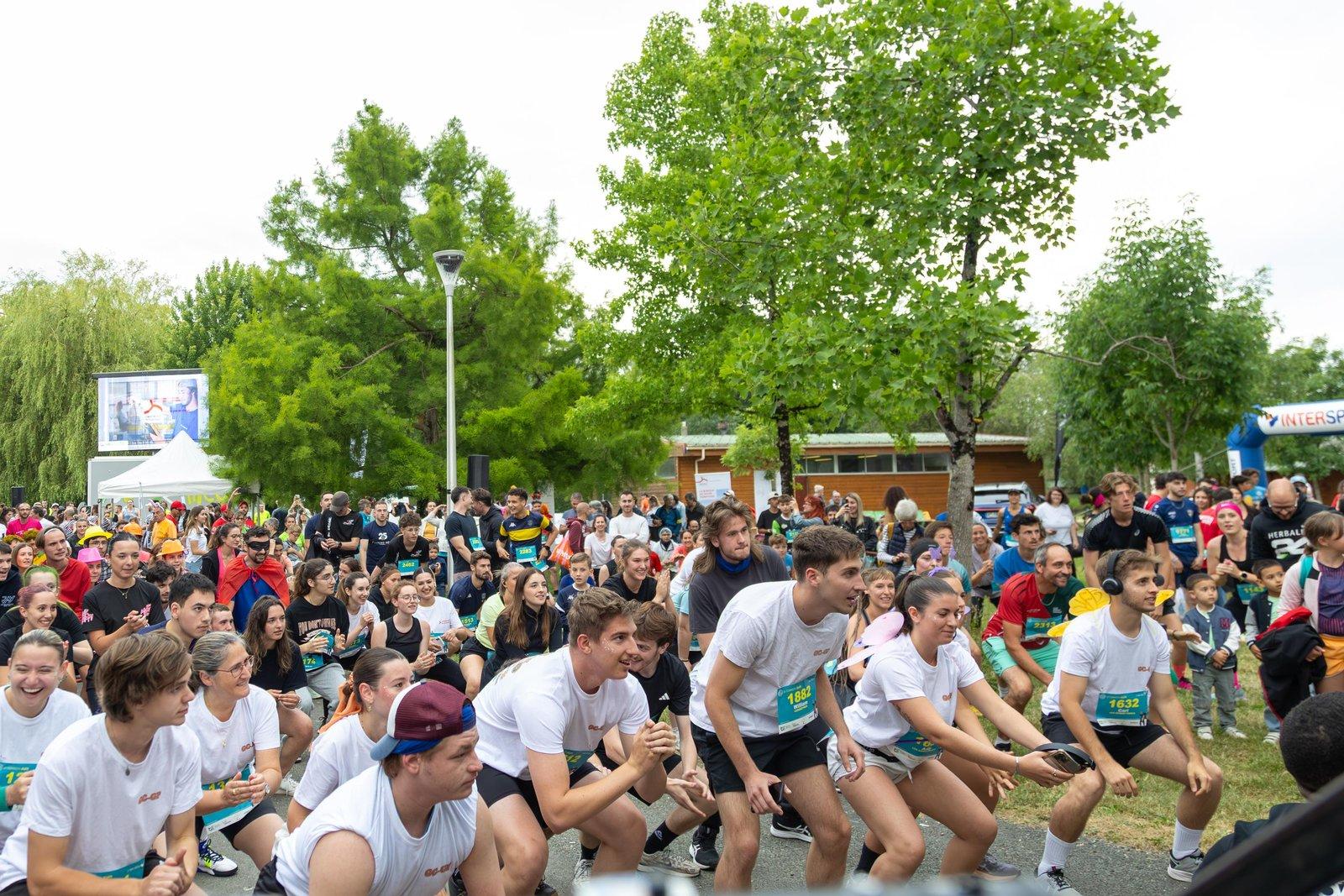 Des centaines de coureurs accroupis pendant l'échauffement collectif, avant le départ