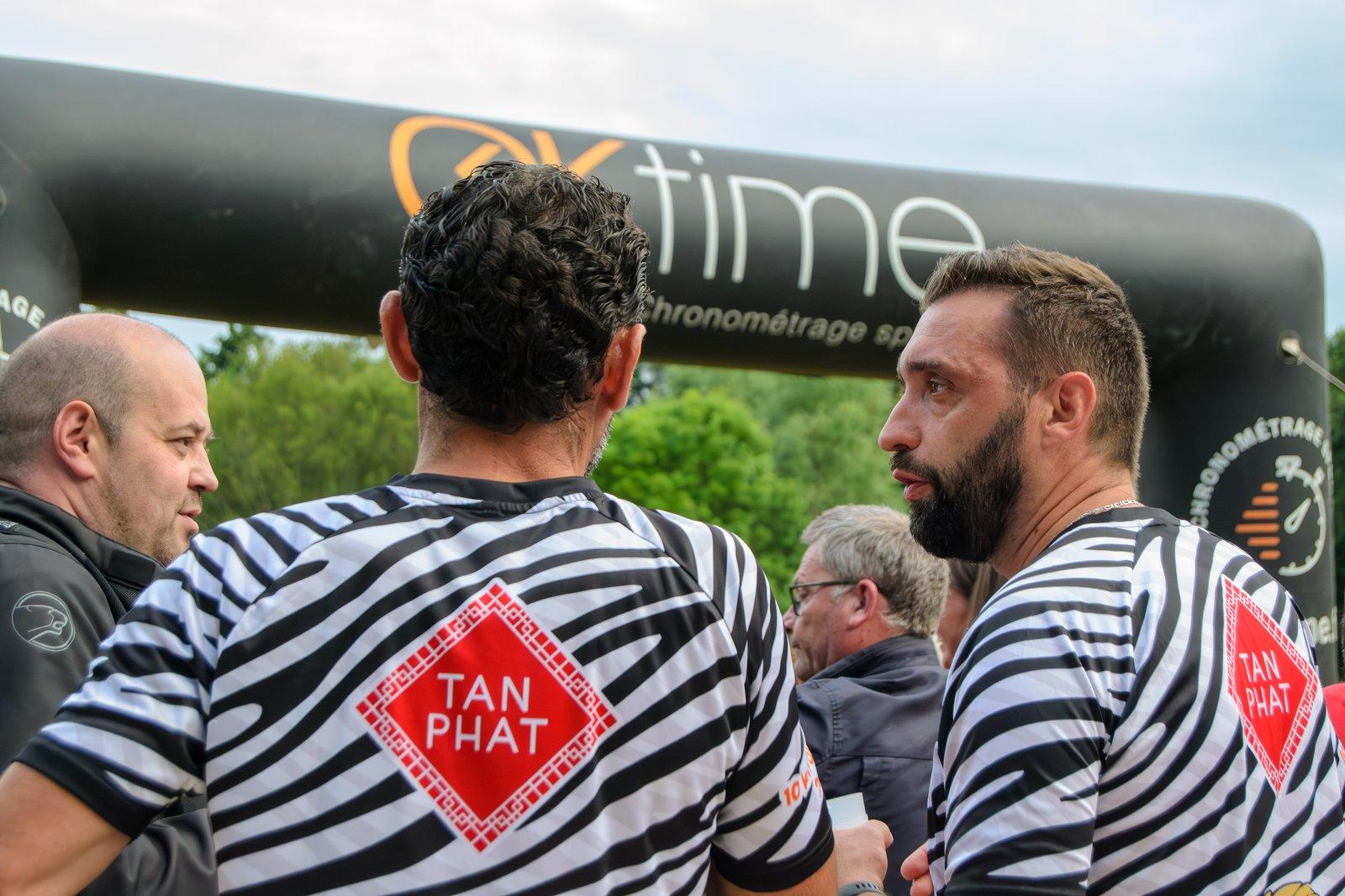 Deux coureurs d'une équipe partenaire discutent sous l'arche de chronométrage